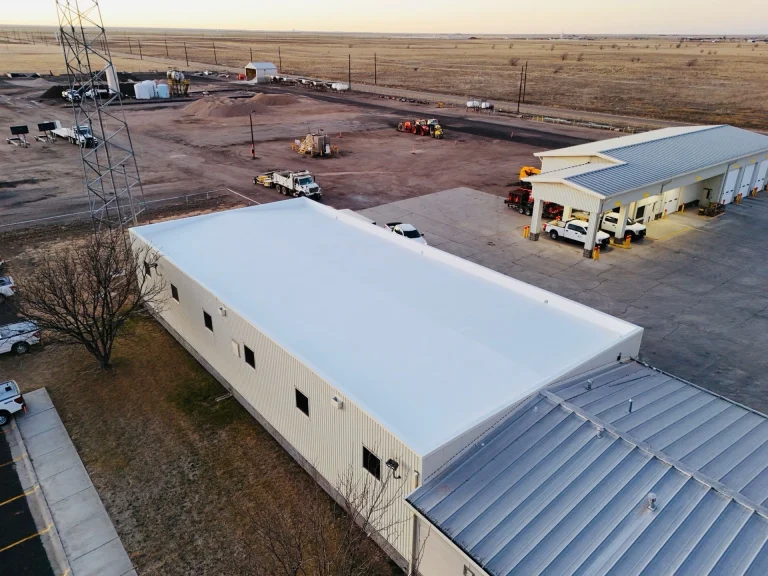 Commercial metal building roof edge where gutter and downspout installation is completed